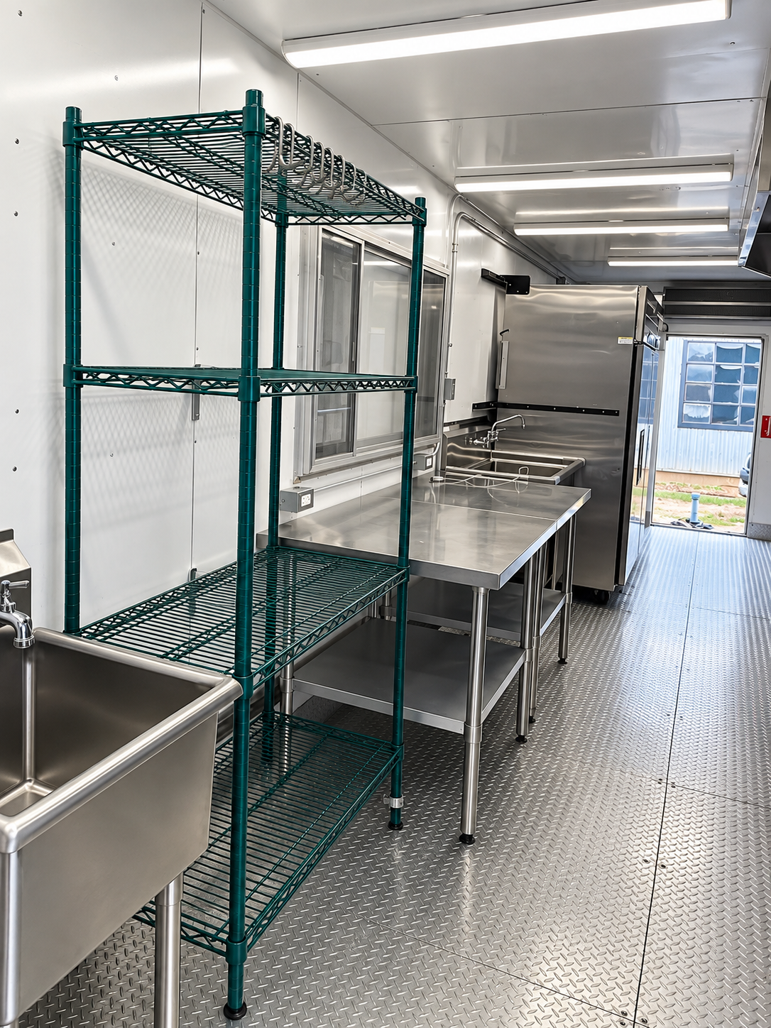 Commercial stainless steel sinks and prep surfaces inside a mobile kitchen wash area